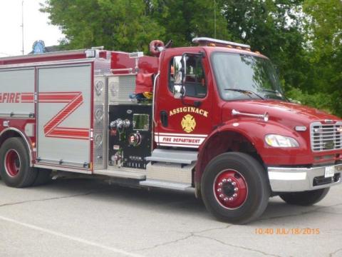 Red fire truck parked on a road, trees in the background.